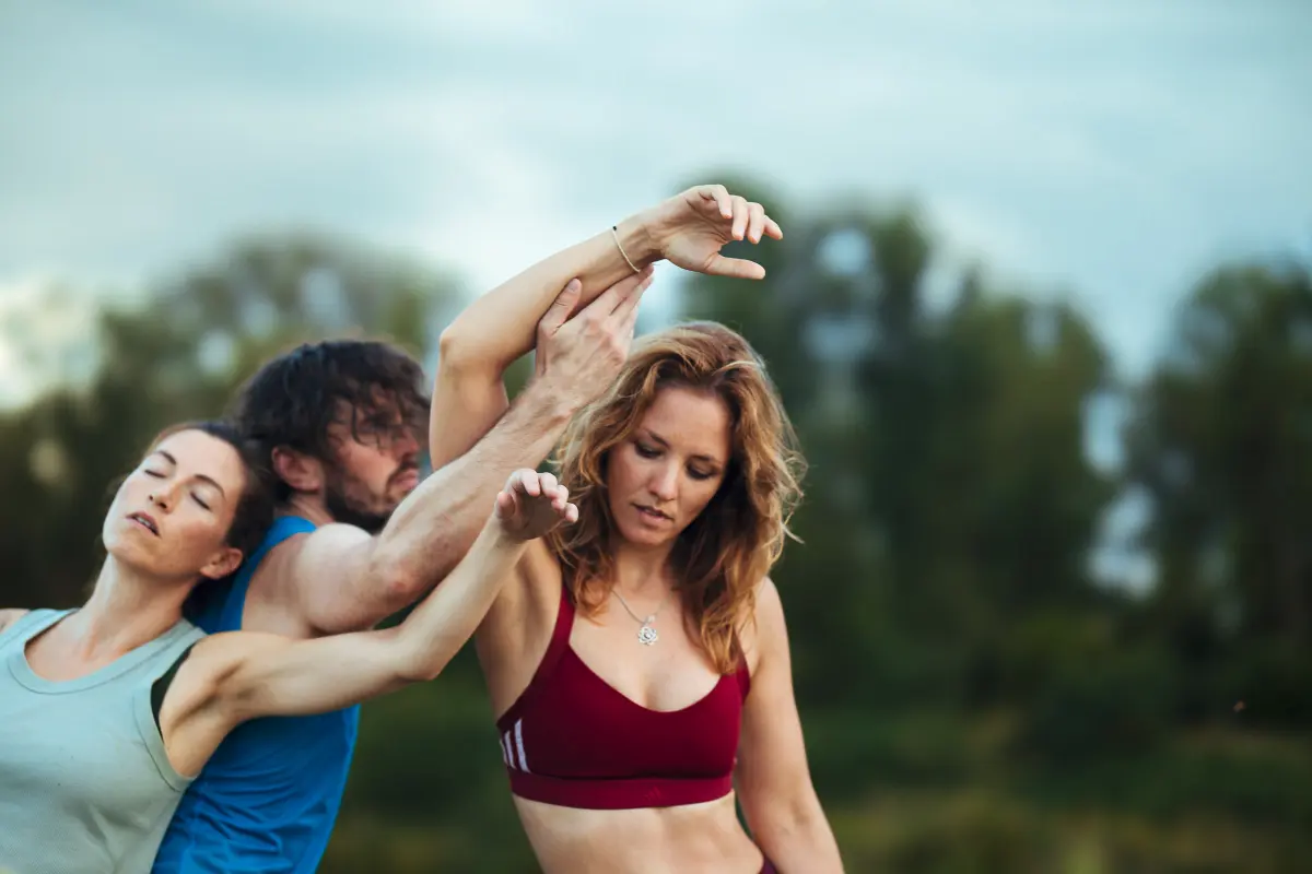 3 Tanzende in der Natur, berühren sich und schließen die Augen.